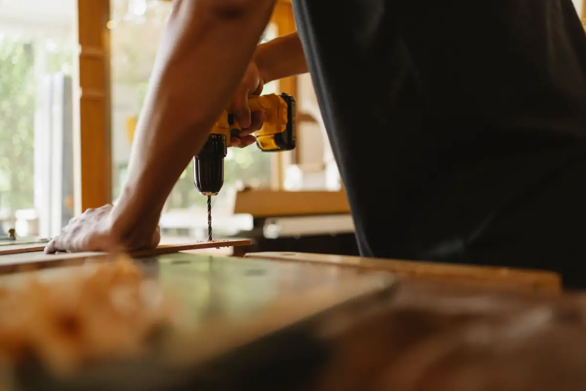 Close-up of a cabinetmaker drilling into wood during custom cabinet construction