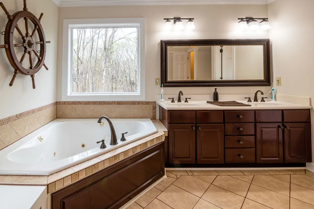 Wood-cabinet double vanity with a whirlpool tub showing wood species and finish detail