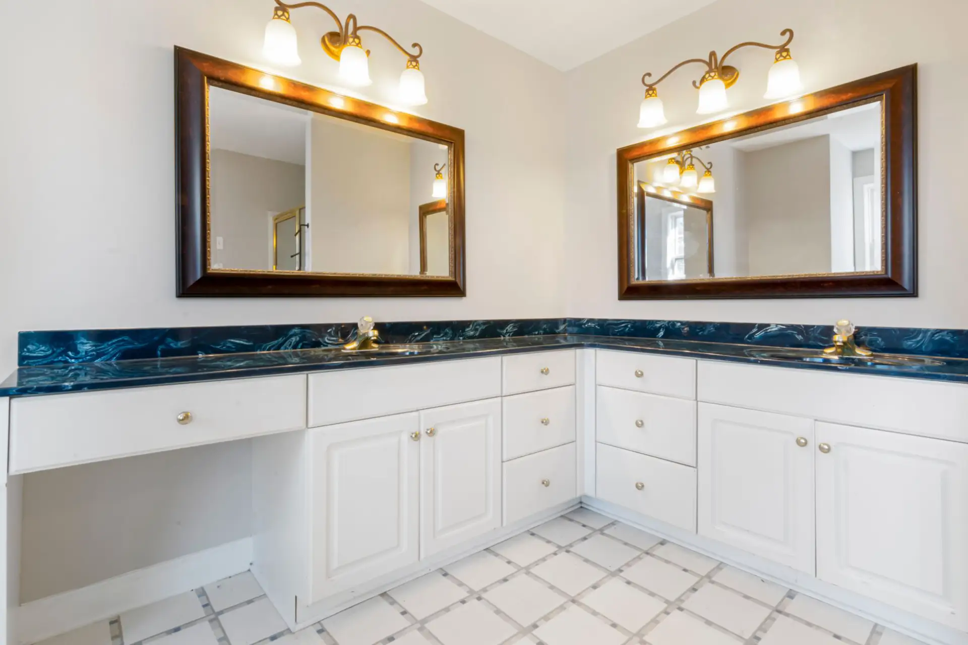 Spacious bathroom with a double-sink custom vanity, granite countertop, and dual mirrors