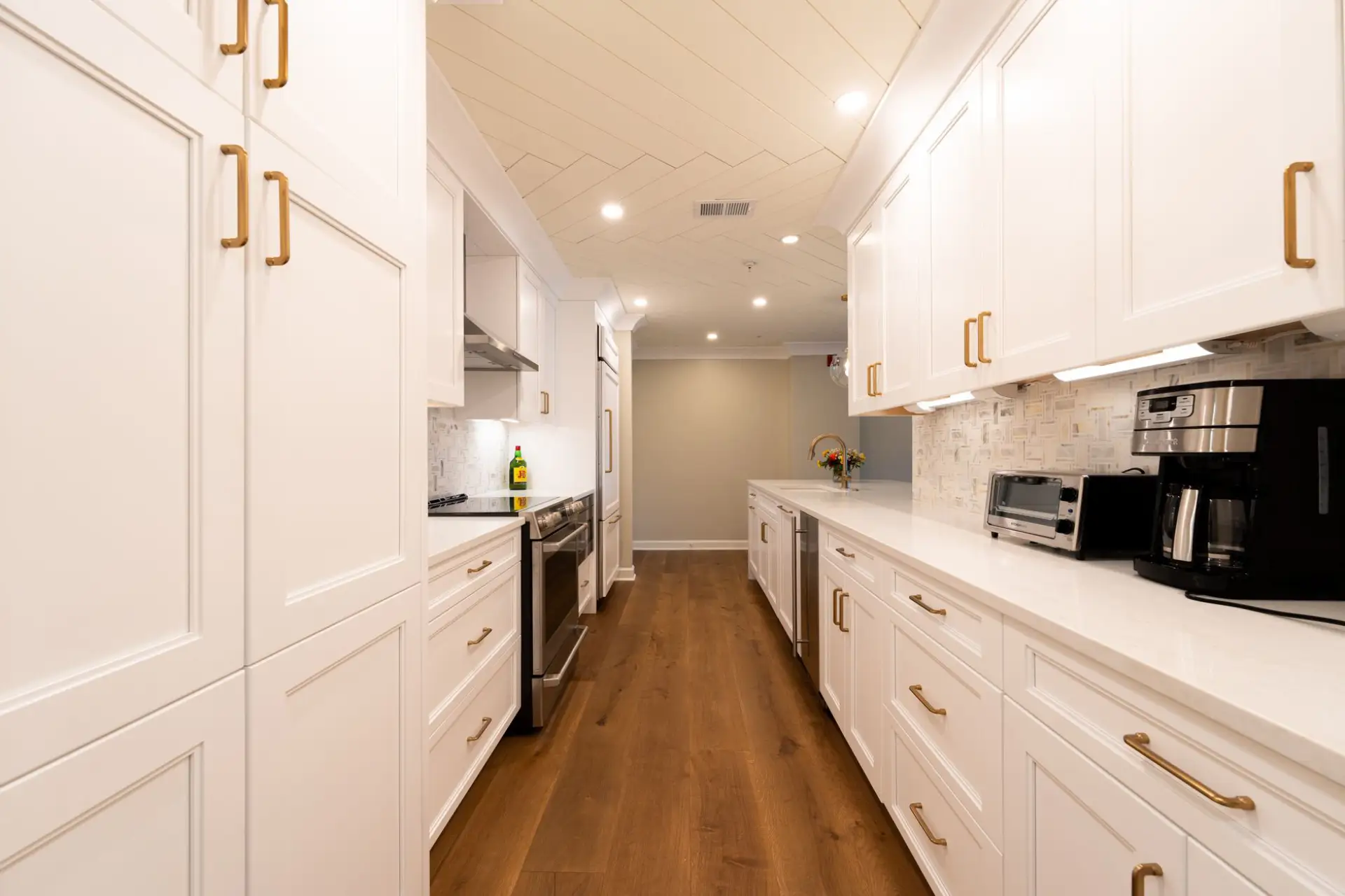 Bright modern kitchen with white refaced cabinets, wood flooring, and appliances