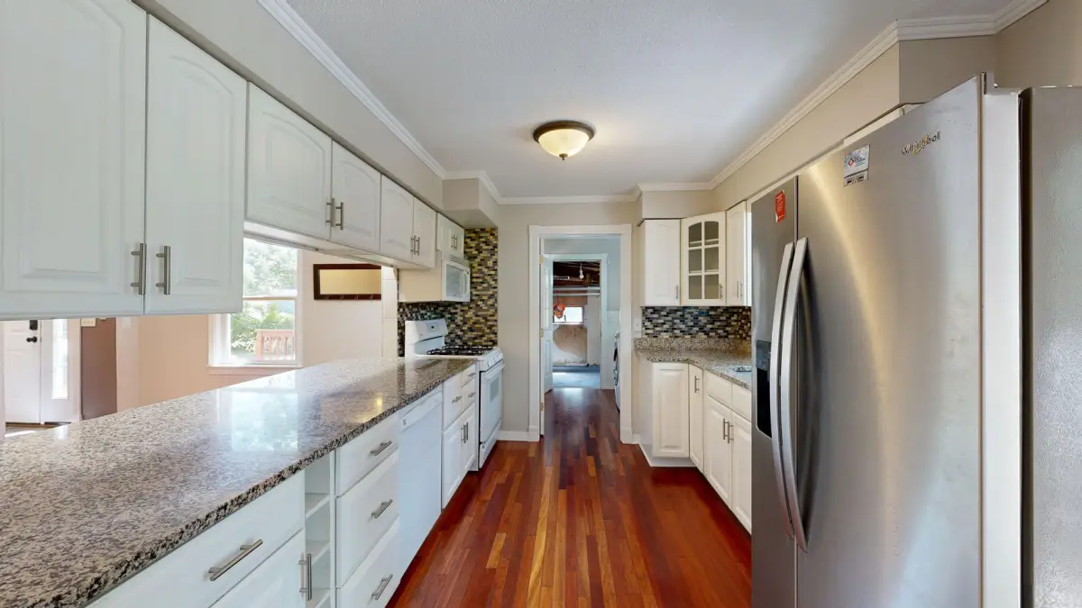 Spacious kitchen with granite countertops and white painted cabinet finish after refacing