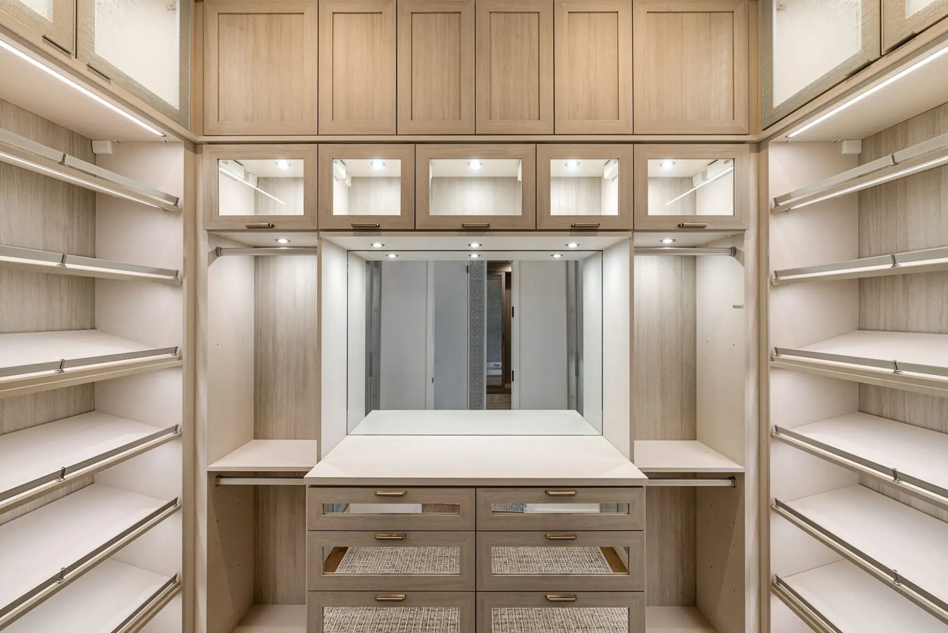 Spacious walk-in closet with wood-finish custom cabinetry and a mirrored vanity