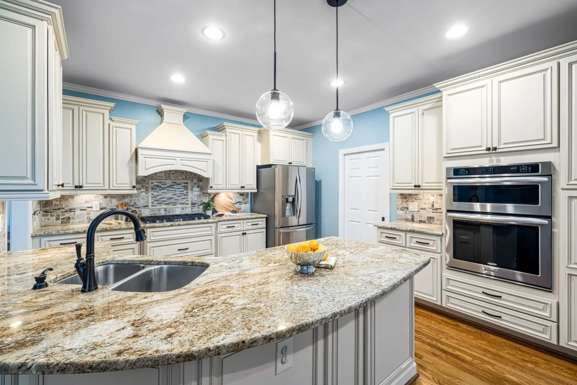 White custom kitchen cabinets with full-overlay doors and a granite-topped island in a Kenosha-area kitchen