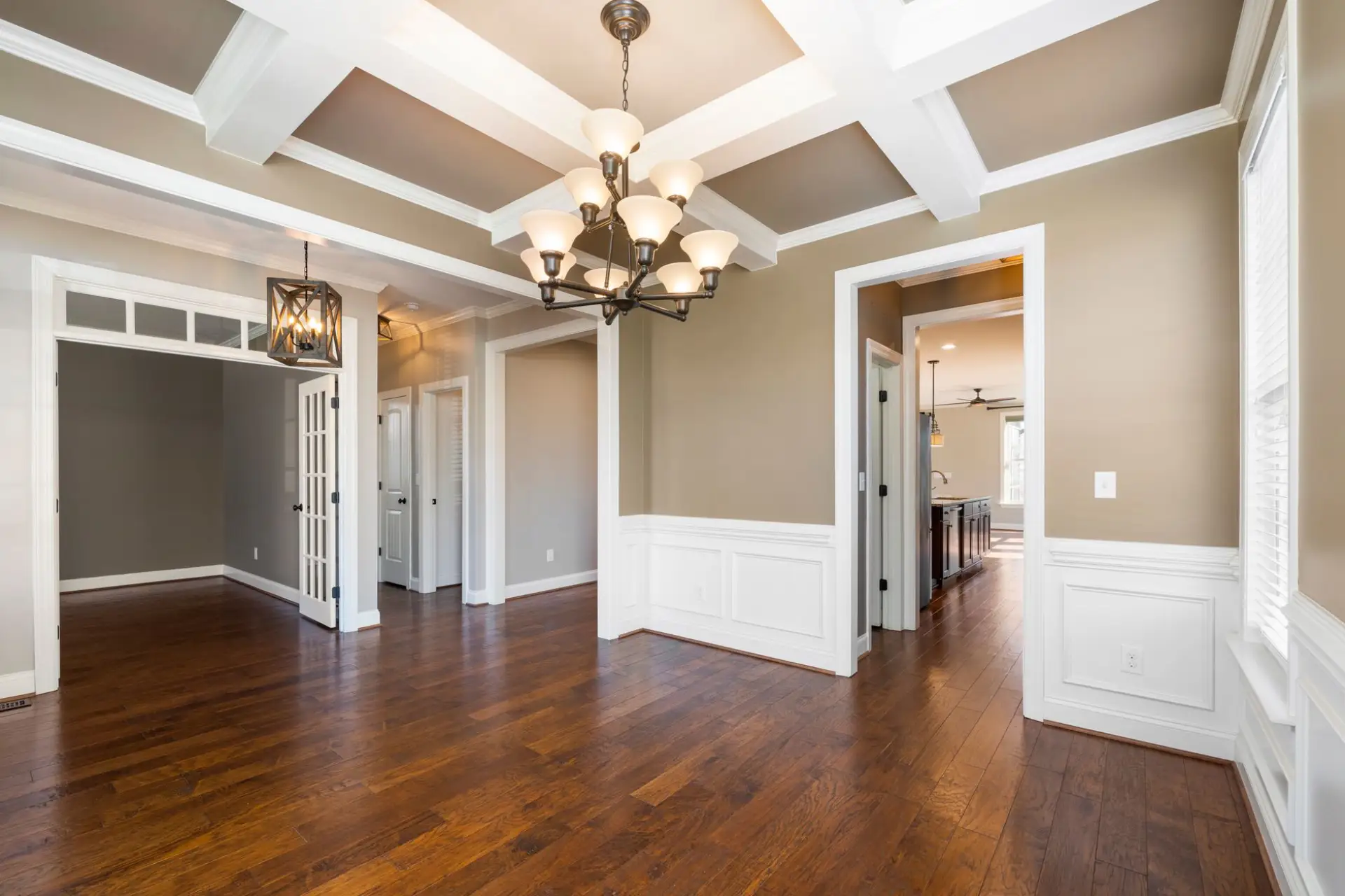 Elegant dining room with coffered ceiling, box-beam trim, and wainscoting