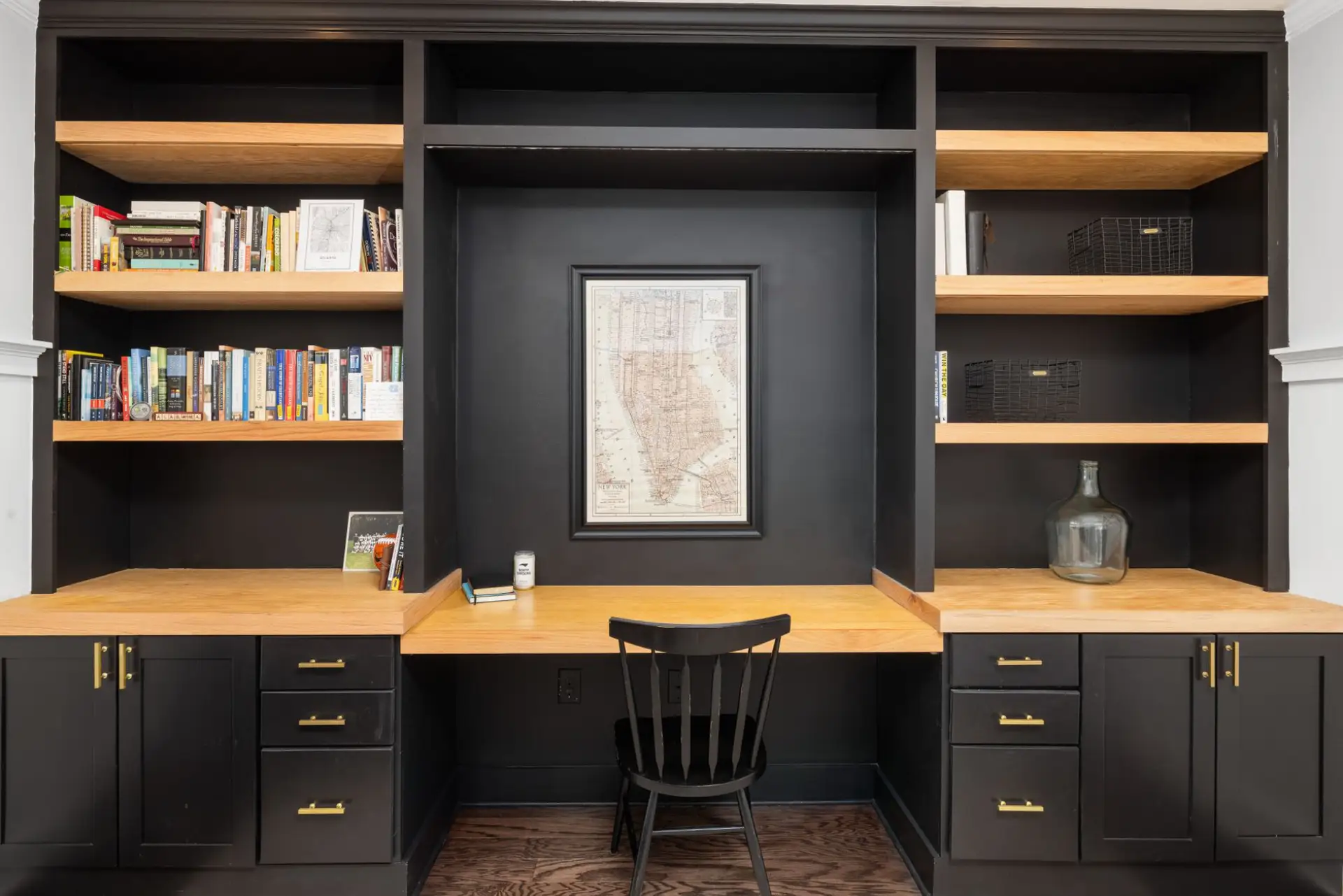 Sleek black and wood home office built-in with bookshelves and a desk workspace