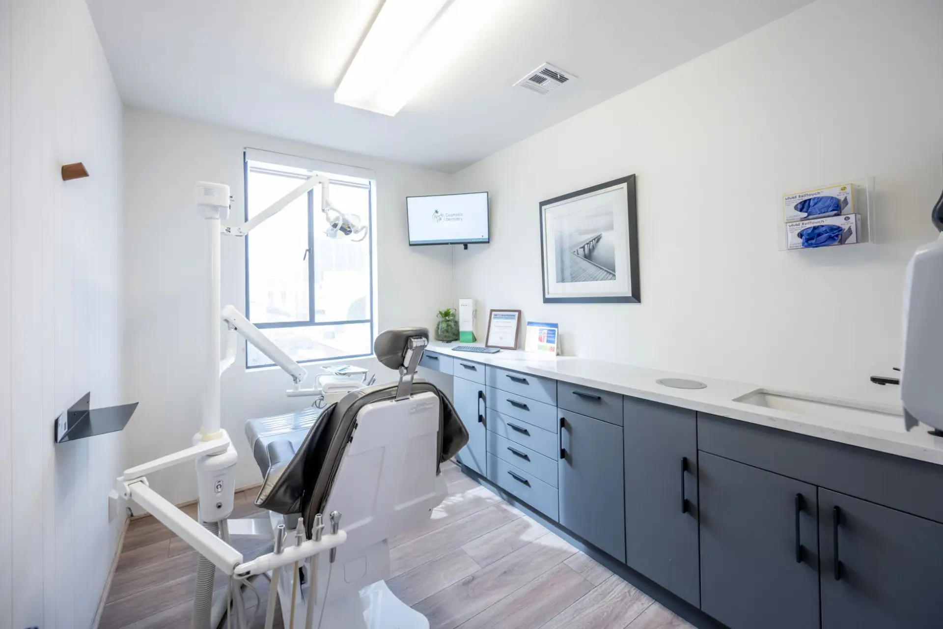 Dental operatory with navy blue cabinetry, sink, and drawer storage