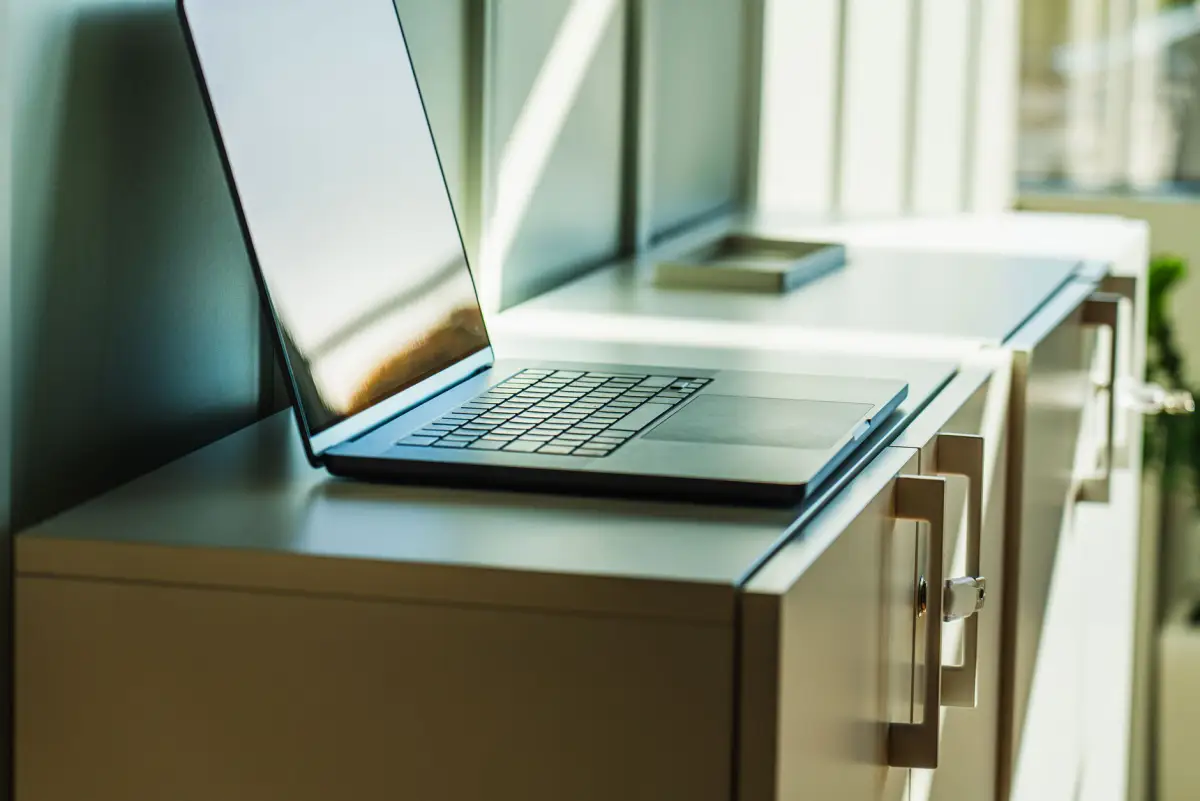 Close-up of a light wood office storage cabinet with a laptop on top