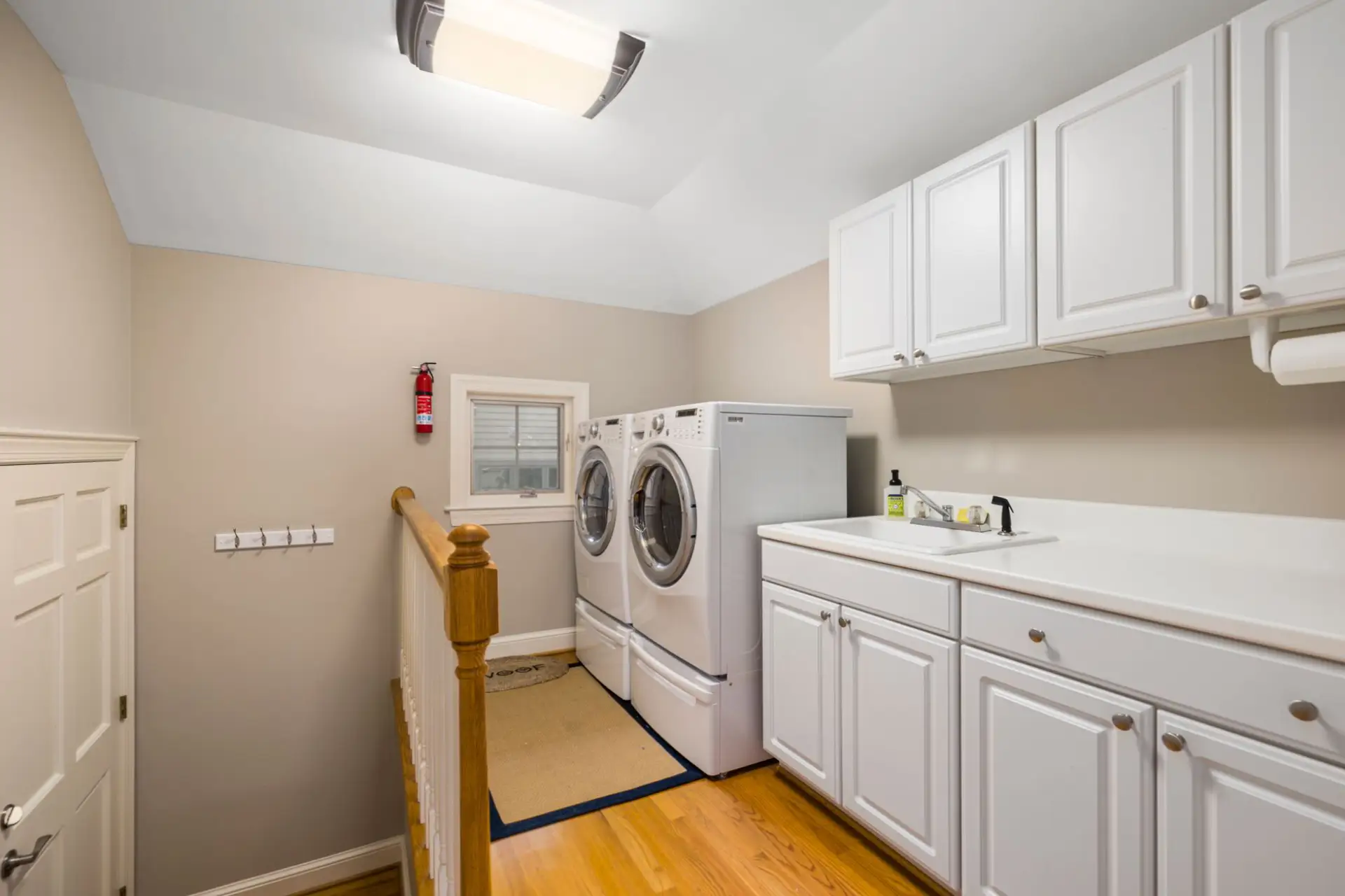Spacious, clean laundry room with modern appliances and white cabinetry